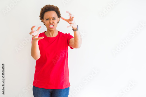 Young beautiful african american woman over white background Shouting frustrated with rage, hands trying to strangle, yelling mad