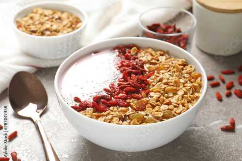 Smoothie bowl with goji berries and spoon on beige marble table