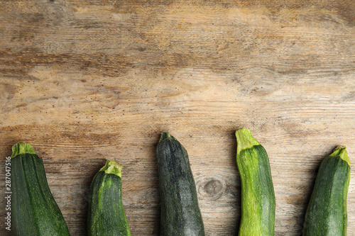 Fresh ripe green zucchini on wooden background, flat lay. Space for text