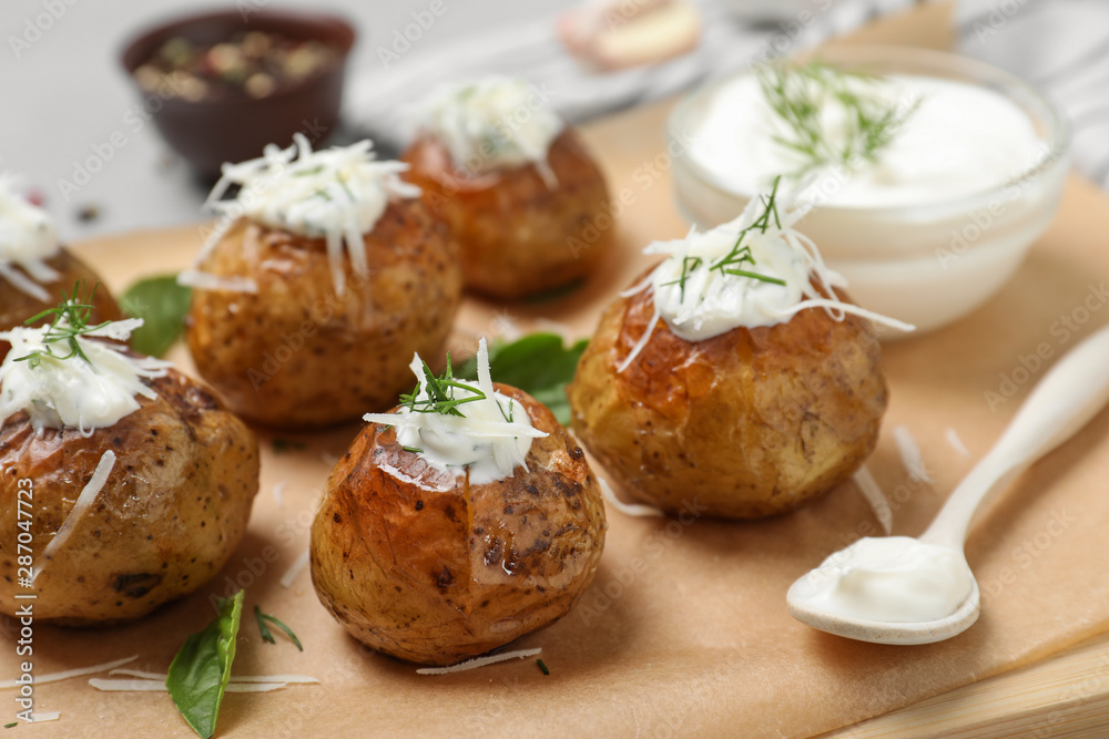 Delicious baked potato with sour cream on wooden board, closeup