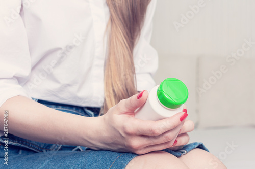 Woman is going to take medication, hand with bottle with pills, closeup, cropped image, toned