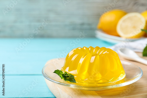 Delicious yellow jelly with mint on light blue wooden table photo