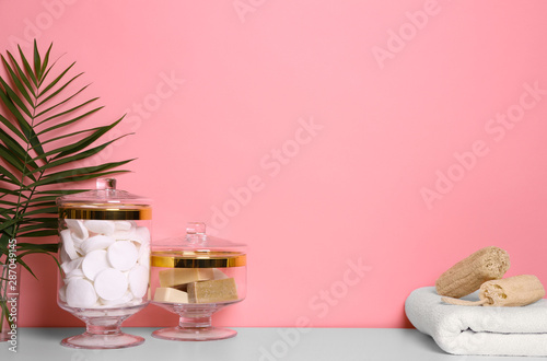 Composition of glass jar with cotton pads on table near pink wall. Space for text