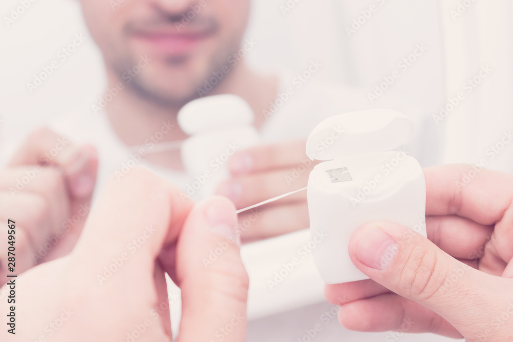 Man looks in the mirror and uses dental floss, man's hands, close up, toned Man looks in the mirror and uses dental floss, man's hands, close up, toned