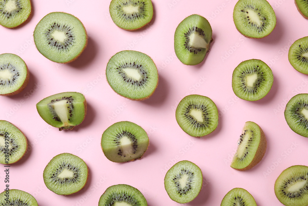 Fototapeta premium Pieces of kiwis on pink background, flat lay