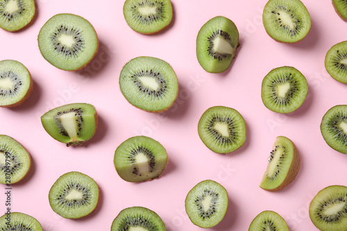 Pieces of kiwis on pink background, flat lay