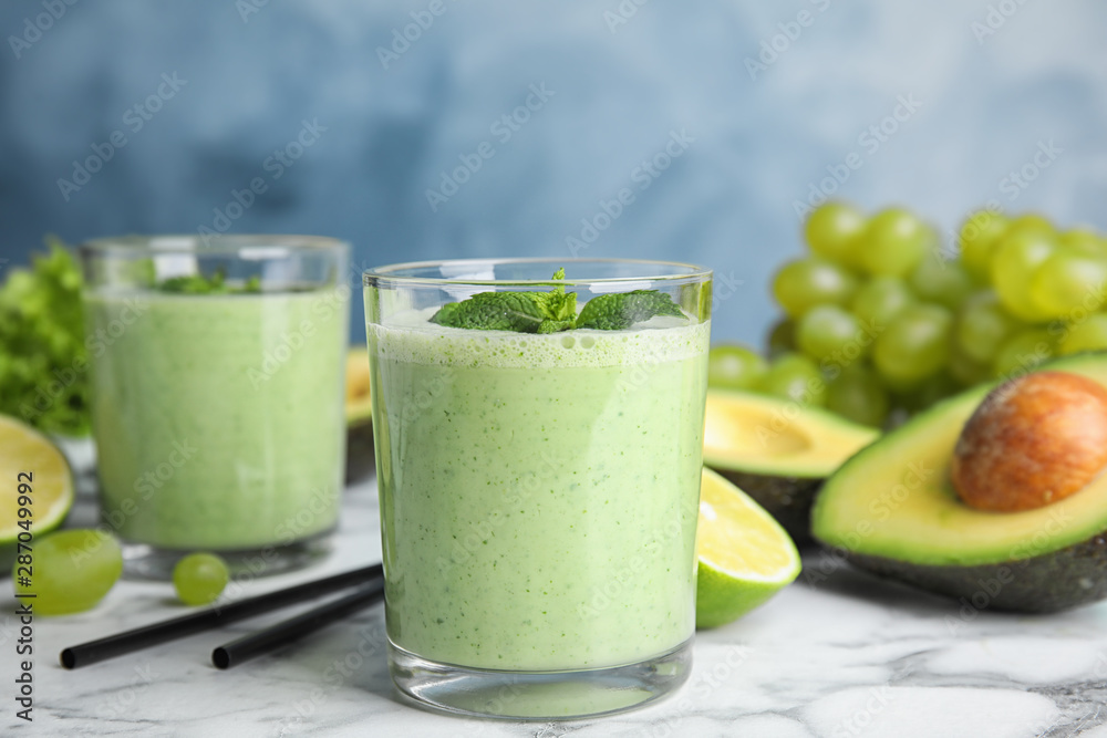 Glasses of tasty avocado smoothie with mint on marble table Glasses of tasty avocado smoothie with mint on marble table