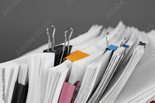 Pile of documents with colorful binder clips, closeup photo