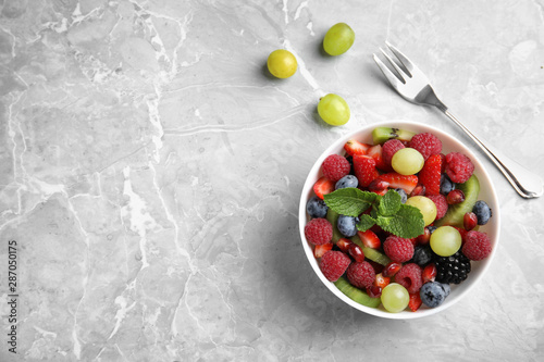Fresh fruit salad on grey marble table, flat lay. Space for text