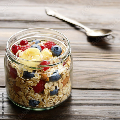 Fruit muesli in glass jar on kitchen wooden table