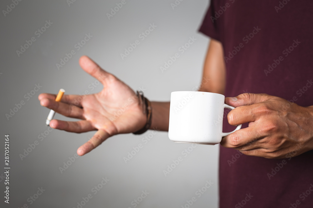 a person holding a coffee cup and a cigarette a person holding a coffee cup and a cigarette