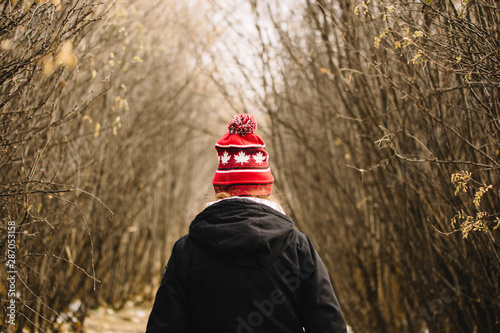 Woman wearing a Canadian toque walking through the woods photo