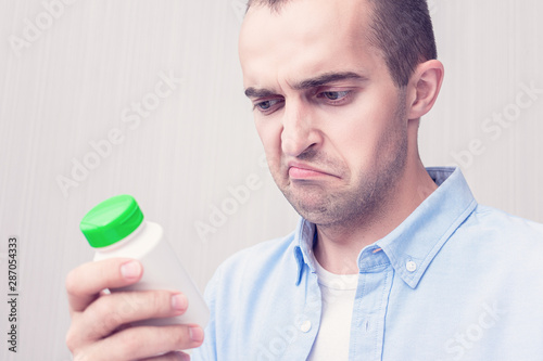 Sad man with a medicine in his hands, man does not want to take pills, portrait, close up, toned