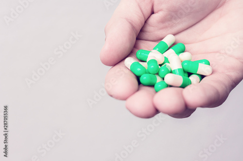 Handful of green capsules, man's hand, closeup, cropped image, copy space, toned