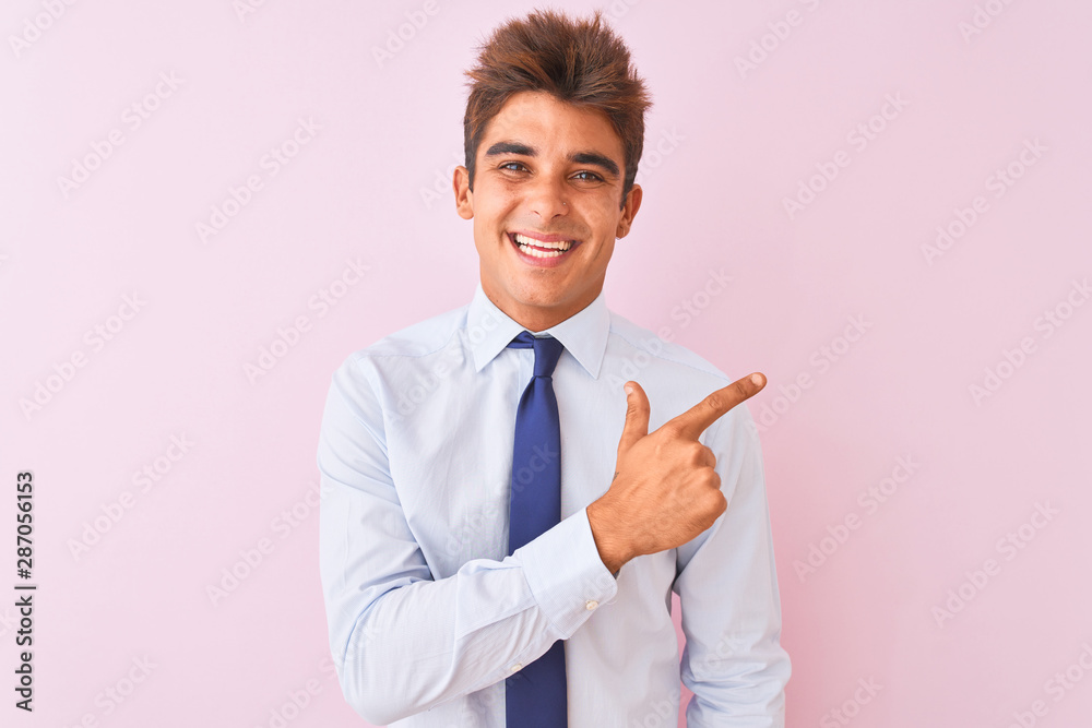Young handsome businessman wearing shirt and tie standing over isolated pink background cheerful with a smile on face pointing with hand and finger up to the side with happy and natural expression Young handsome businessman wearing shirt and tie standing over isolated pink background cheerful with a smile on face pointing with hand and finger up to the side with happy and natural expression