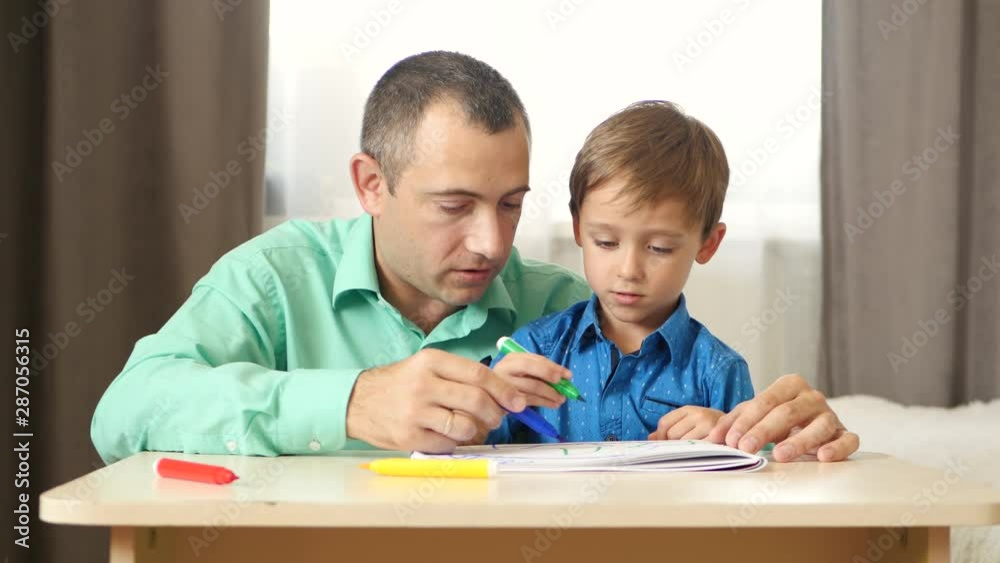 Happy white family at home. Father and child helps son to draw. Education, parenthood and relationships, teaching children. Happy white family at home. Father and child helps son to draw. Education, parenthood and relationships, teaching children.