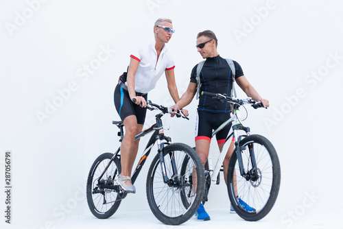 Man and woman with bicycles posing on a light background.