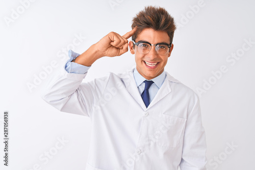 Young handsome sciencist man wearing glasses and coat over isolated white background Smiling pointing to head with one finger, great idea or thought, good memory