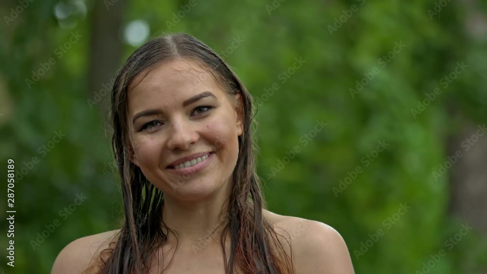 Woman in woods soaked under rain shower shows her giggles,close up Woman in woods soaked under rain shower shows her giggles,close up