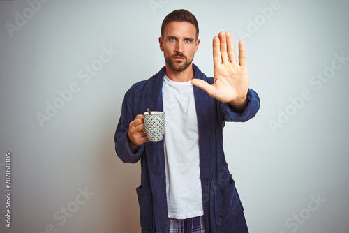 Man wearing comfortable pajamas and robe drinking cup of coffee over isolated background surprised with an idea or question pointing finger with happy face, number one