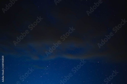 blue starry sky through gray clouds © Artoym