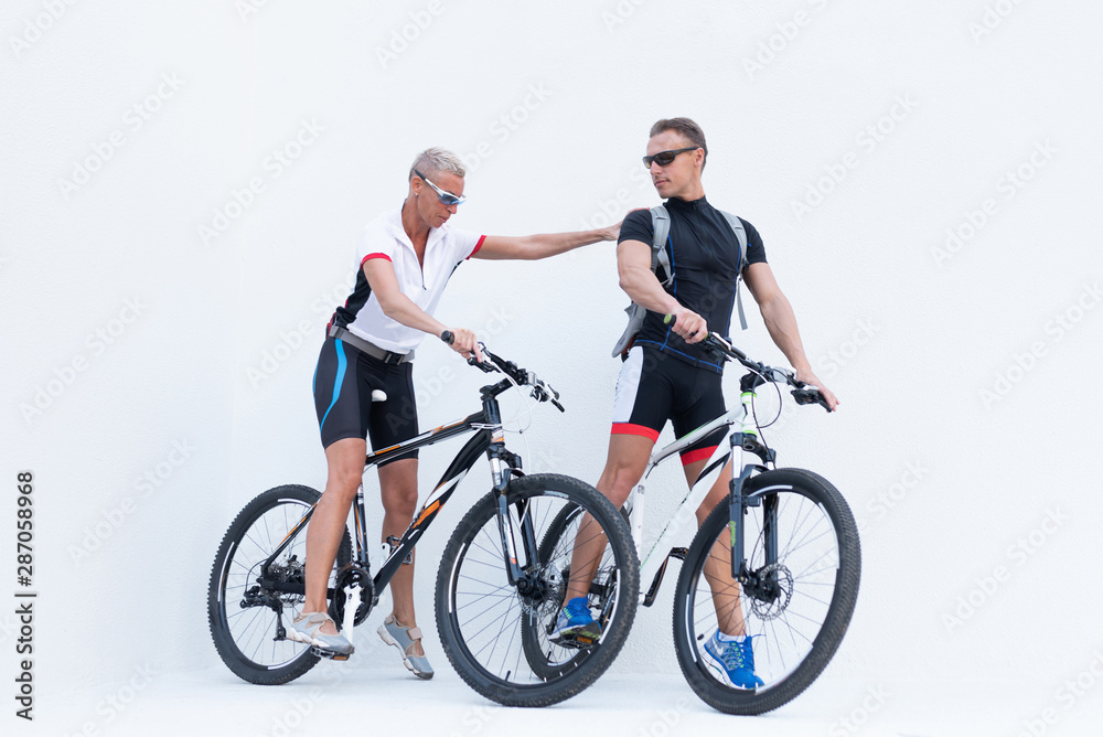 Man and woman with bicycles, a woman holds a man by the shoulder, on a light background. Man and woman with bicycles, a woman holds a man by the shoulder, on a light background.