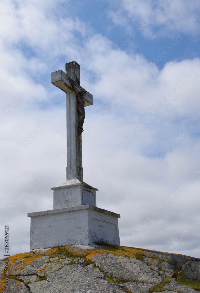 side view of a large crucifix on top of a hill, clouds in the background  