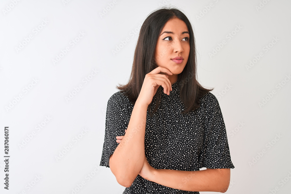 Young chinese woman wearing elegant t-shirt standing over isolated white background with hand on chin thinking about question, pensive expression. Smiling with thoughtful face. Doubt concept. Young chinese woman wearing elegant t-shirt standing over isolated white background with hand on chin thinking about question, pensive expression. Smiling with thoughtful face. Doubt concept.