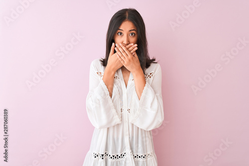 Young chinese woman wearing summer shirt standing over isolated pink background shocked covering mouth with hands for mistake. Secret concept.