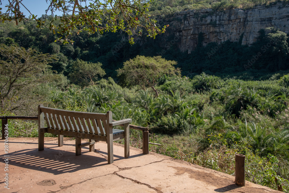 A bench overlooking the cliffs and dense vegetation along an African river. A bench overlooking the cliffs and dense vegetation along an African river.