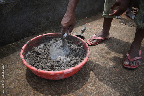 A person plastering cement concrete mixture using a trowel in building works