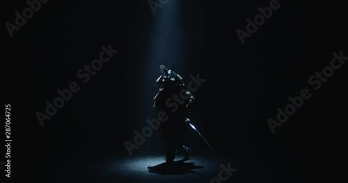 Asian man in traditional samurai costume stepping into the light with his sword prepared in hands, isolated on black background - culture, tradition concept 4k footage photo