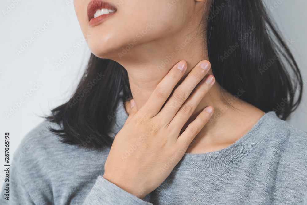Symptoms from flu season in winter concepts. Close up woman touching her neck and suffering from sore throat. Symptoms from flu season in winter concepts. Close up woman touching her neck and suffering from sore throat.