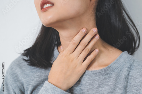 Symptoms from flu season in winter concepts. Close up woman touching her neck and suffering from sore throat.