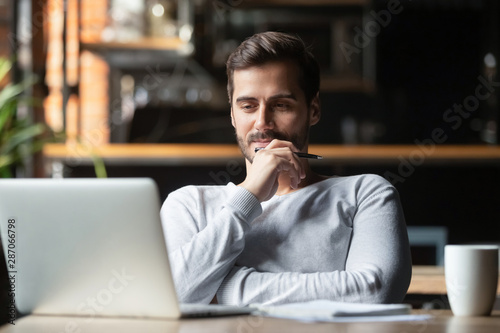 Thoughtful businessman think of online project looking at laptop photo
