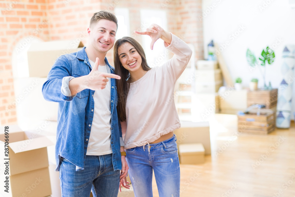 Beautiful young couple moving to a new house smiling making frame with hands and fingers with happy face. Creativity and photography concept. Beautiful young couple moving to a new house smiling making frame with hands and fingers with happy face. Creativity and photography concept.