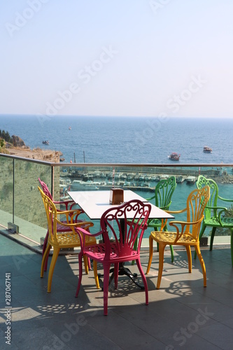 Bunte St  hle und Tisch im Caf   mit Blick auf das Meer