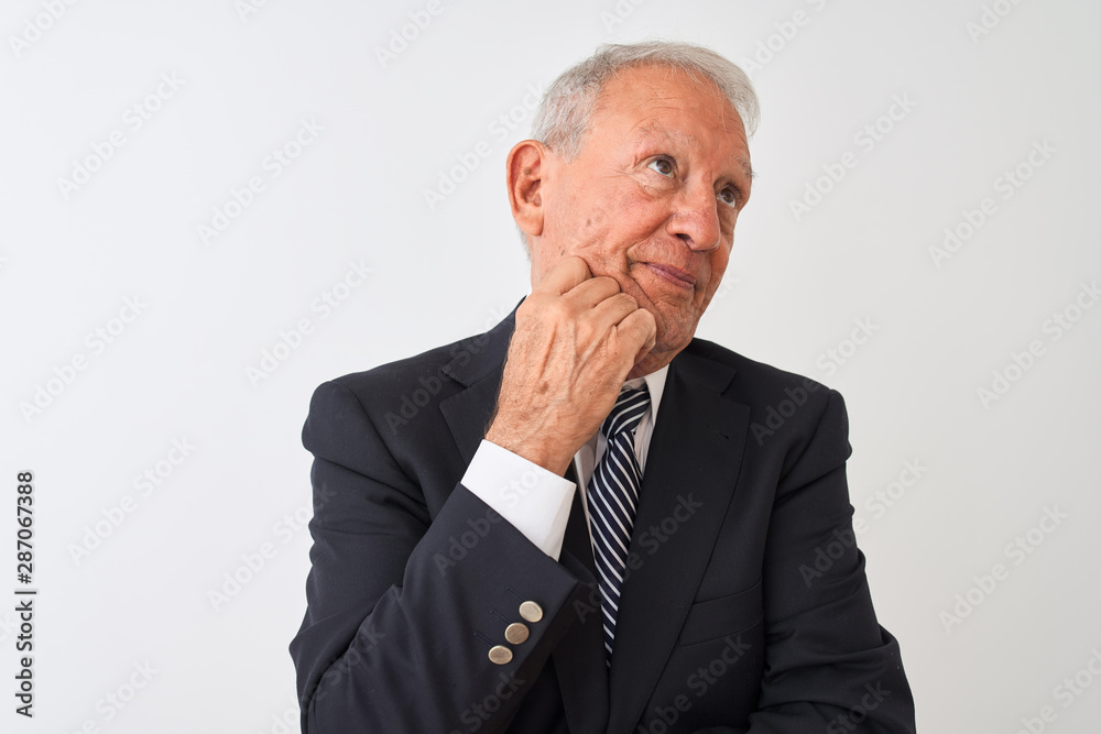 Senior grey-haired businessman wearing suit standing over isolated white background with hand on chin thinking about question, pensive expression. Smiling with thoughtful face. Doubt concept. Senior grey-haired businessman wearing suit standing over isolated white background with hand on chin thinking about question, pensive expression. Smiling with thoughtful face. Doubt concept.