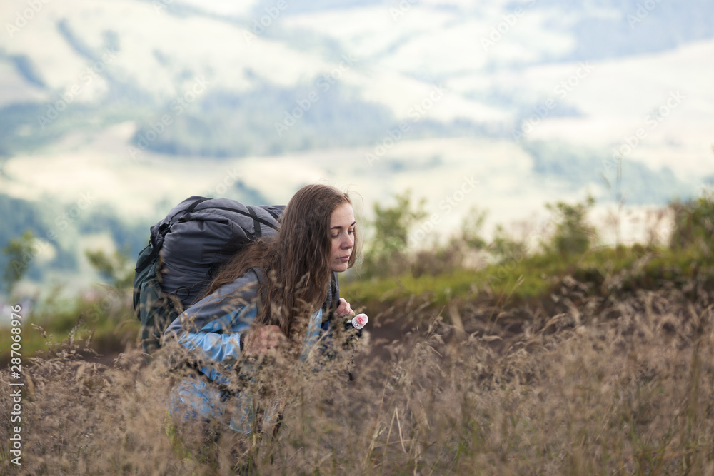 Girl hiker with a backpack climbing up a mountain Girl hiker with a backpack climbing up a mountain