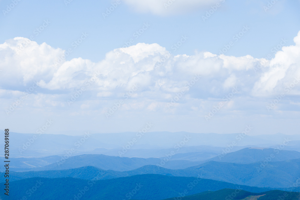 Cloud landscape with blue silhouettes of mountains.