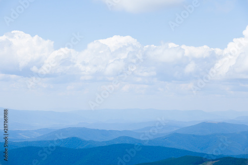 Cloud landscape with blue silhouettes of mountains.