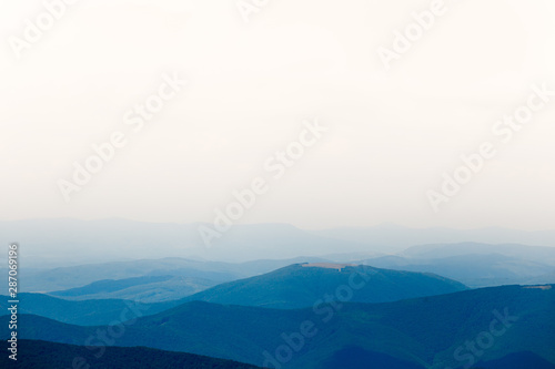 Mountain view with blue hills and white sky in the fog.