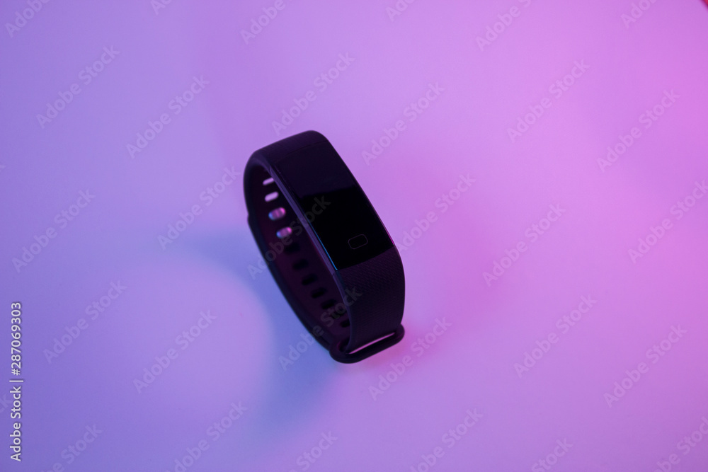 Black fitness tracker bracelet on white neon lights in pink and blue . Bright and impressive Black fitness tracker bracelet on white neon lights in pink and blue . Bright and impressive