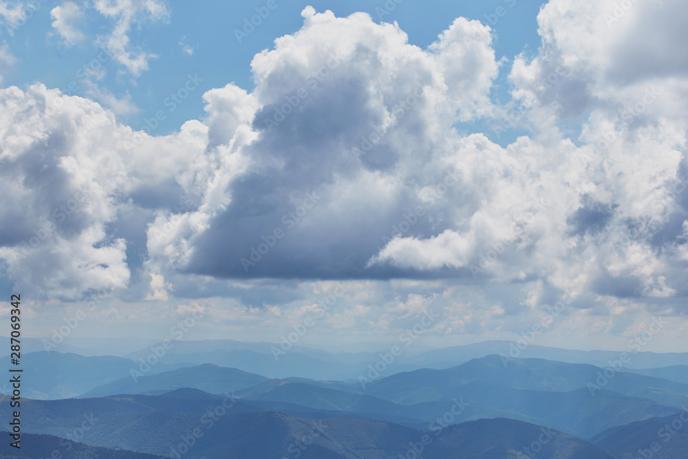 Cloud landscape with blue silhouettes of mountains.