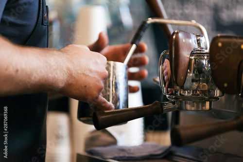 Barista steaming milk for hot cappuccino with machine