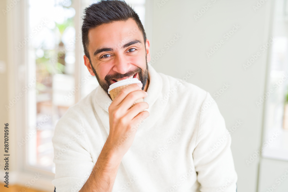 Handsome man smiling while enjoying drinking a take away coffee in the morning Handsome man smiling while enjoying drinking a take away coffee in the morning