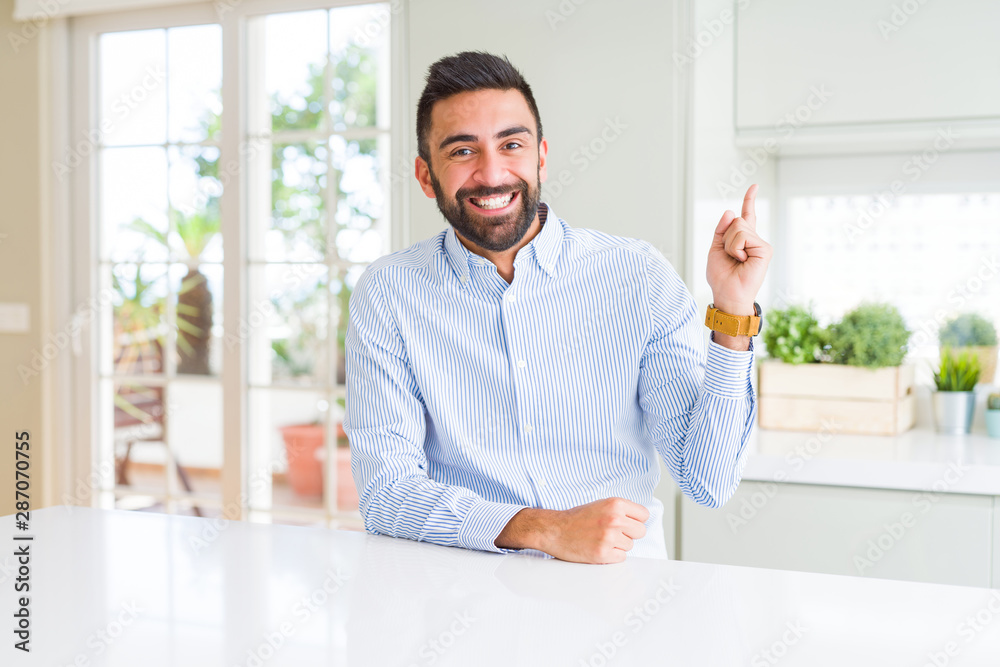 Handsome hispanic business man with a big smile on face, pointing with hand and finger to the side looking at the camera.