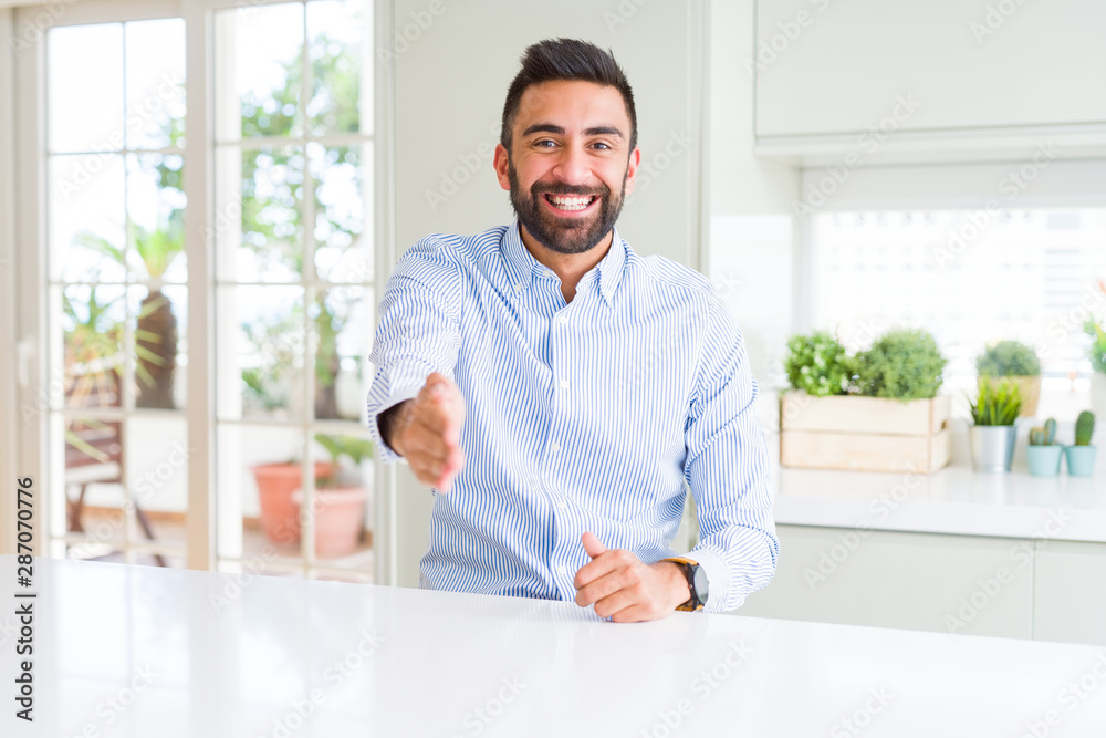 Handsome hispanic business man smiling friendly offering handshake as greeting and welcoming. Successful business.
