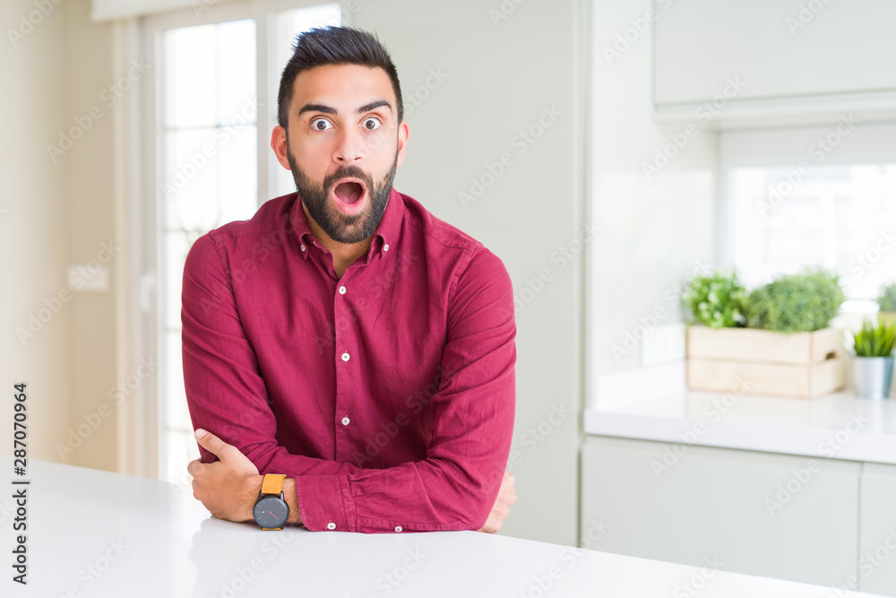 Handsome hispanic business man afraid and shocked with surprise expression, fear and excited face.