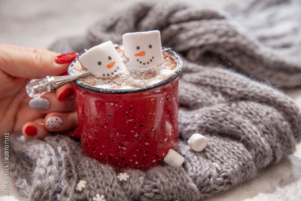 Red mug with hot chocolate with melted marshmallow snowman in a woman hands - obrazy, fototapety, plakaty 